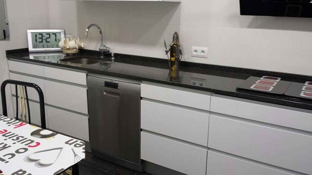 Armarios inferiores blancos y encimera negra en cocina finalizada